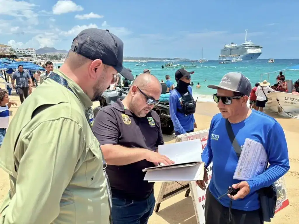 Vista de playa El Médano en Cabo San Lucas, con turistas y sombrillas