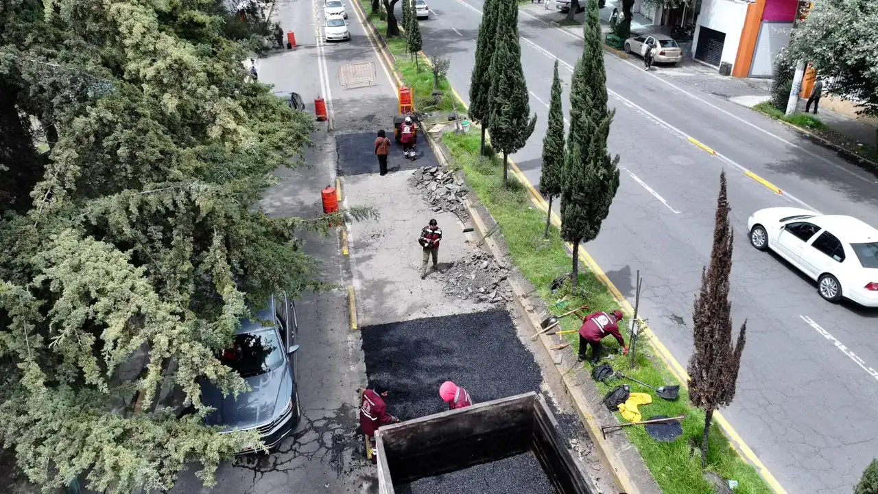 Trabajadores de bacheo en una calle de Toluca con maquinaria y señalamientos