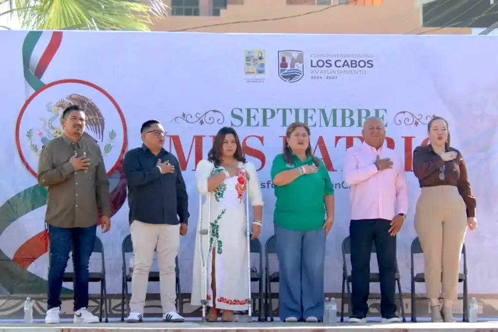 Personas participan en un desfile cívico-militar en una calle de Cabo San Lucas