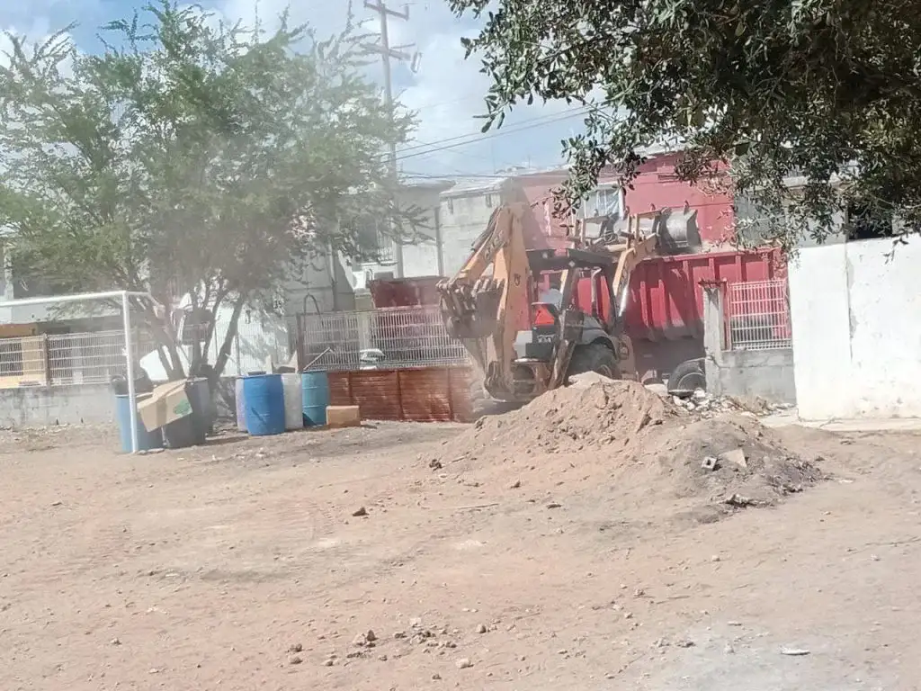 Trabajadores de servicios públicos realizando labores de limpieza en el exterior de una escuela primaria
