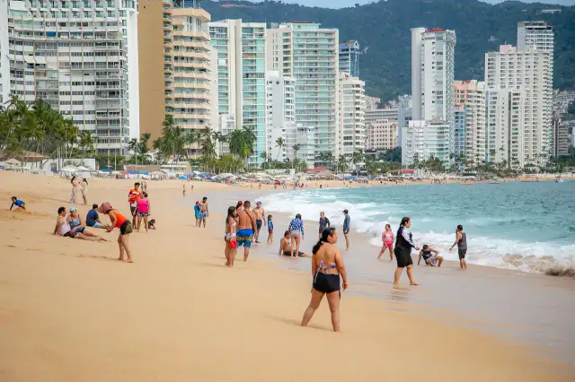 Turistas caminando por la zona costera de un destino de playa en Guerrero