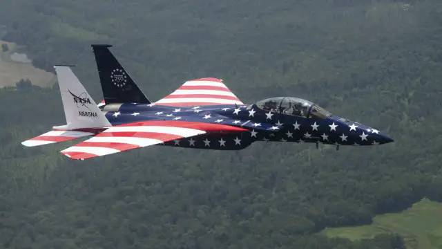 Dos aviones de combate, un F-15 y un F/A-18, con pintura roja, blanca y azul estacionados en una pista